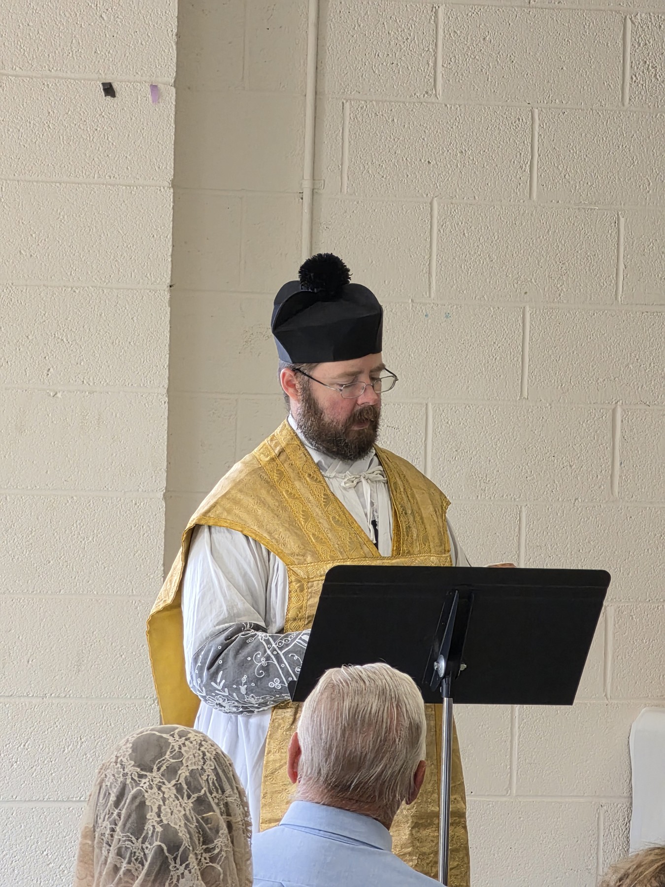 Fr. Timothy Scott Hoopes speaking at a lectern in gold vestments.