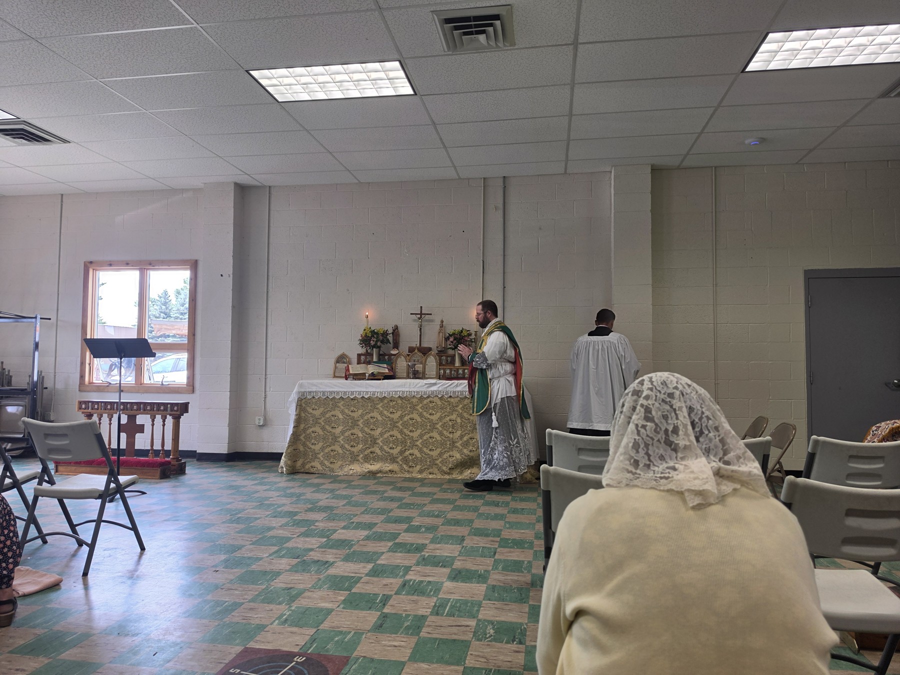Hoopes celebrating Mass at an altar in the former fire station in Topinabee, with worshippers in the foreground.